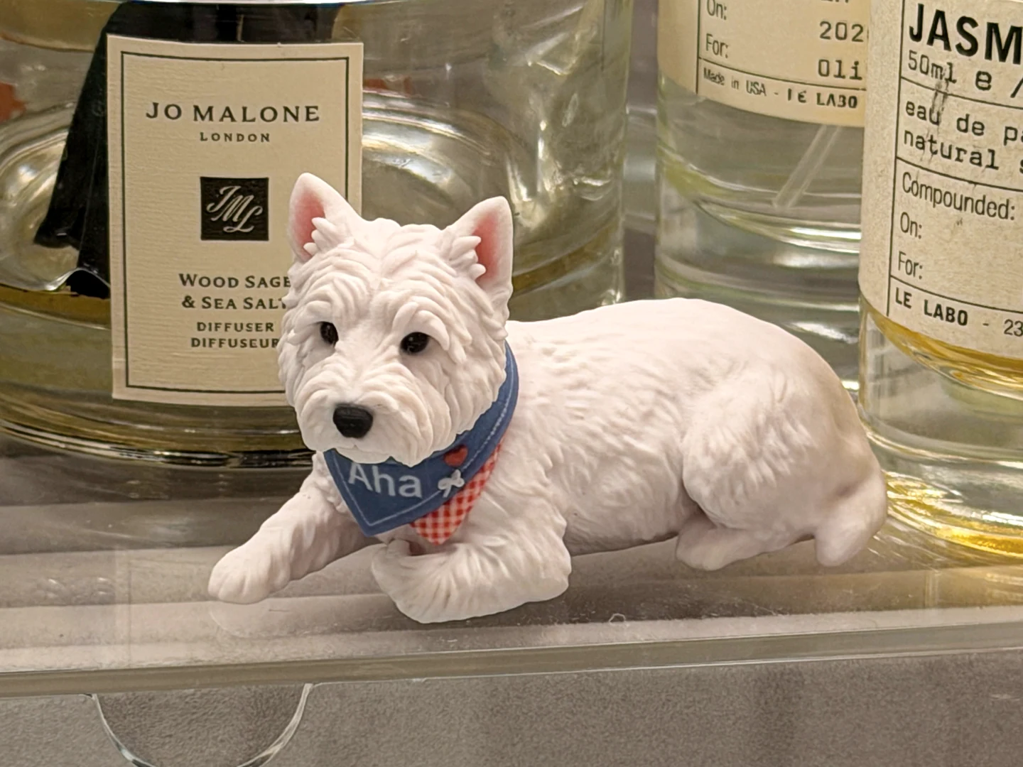 ガラスのフレグランスボトルの前に置かれた、完成したAhaの犬フィギュアの実写写真